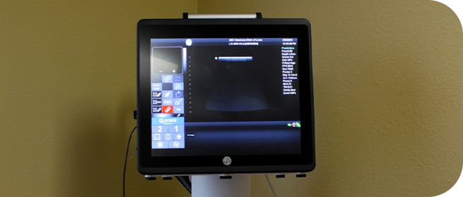 Computer monitor on a stand displaying a graphical interface with various icons and menu options.